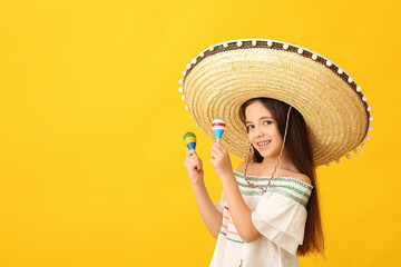 Funny Mexican girl in sombrero hat and with maracas on color background