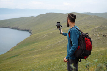Man with backpack takes picture of the green bank on his phone Travel photography Copy space Wild nature