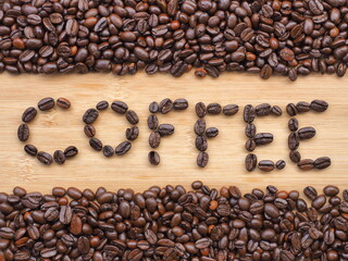 Coffee beans forming the word "Coffee" on wooden background, Coffee word made of coffee beans.