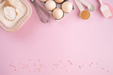 Frame of food ingredients for baking on gently pink pastel background. Cooking flat lay with copy...