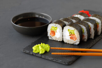 Maki sushi roll served on stone plate on gray background