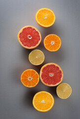 Creatively laid out citrus fruits on gray background. Top view of oranges, lemons, tangerines, grapefruit.Citrus juice ingredients, food background