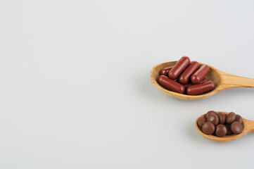 Brown pills and capsules in a wooden spoon on a gray background, Herbal Medicine,Coronavirus; Treatment; Virus