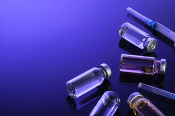 Syringes, small bottles, glass vials with vaccine, medicine on a dark blue background. Coronovirus...