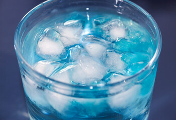 glass of water with blue ice cubes