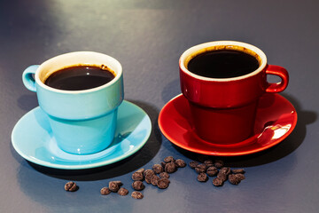 red and blue cups of coffee with chocolate on grey background