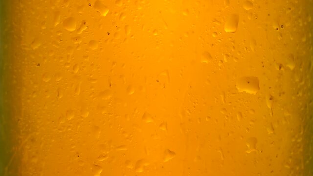Cold beer in a glass bottle with dripping condensation drops and air bubbles. Beer background with drops of cold water condensate