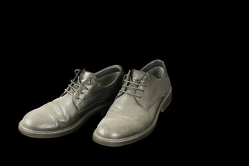 Old black men dusty leather shoes isolated on black background, unemployment concept