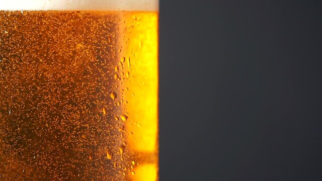Cold beer in a glass bottle with dripping condensation drops and air bubbles. Beer background with drops of cold water condensate