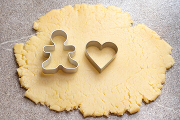 Cooking homemade cookies concept. Dough with blanks of cookies in the shape of one gingerbread man...
