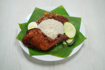 Nasi Lemak dish with chicken drum stick on white wooden verneer