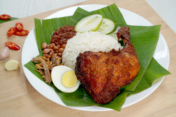 Nasi Lemak dish with chicken drum stick on white wooden verneer