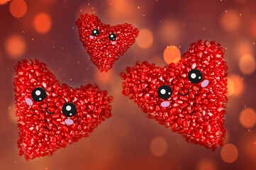 Three hearts made of pomegranate seeds with muzzles on a background with bokeh.