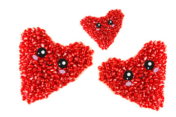 Three hearts from pomegranate seeds with muzzles on a white background.
