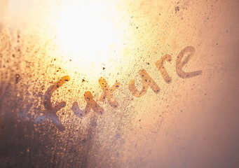 The word future on the window with water drops on sunny background. Fogged window calligraphy. Bright Future concept