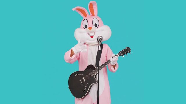 Guitarist plays acoustic guitar, sings song to retro vintage classic microphone, celebrates Happy easter
