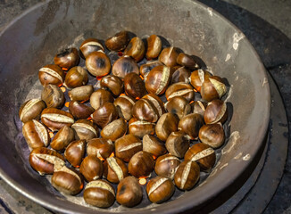 chestnuts being roasted in a skillet with holes on a woodfire in South Tyrol, northern Italy