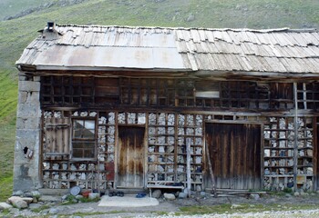 There is a fascinating stone house in front of a valley filled with green grass.