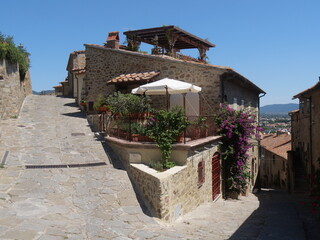 Naklejka premium Solti Square of Castiglione della Pescaia with a street that goes up to the Castle and a road that goes down between the houses.