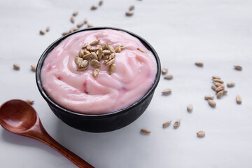 Strawberry yogurt with sunflower seeds in black cup. food for health concept.