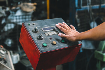 Fototapeta premium Close up hand of machine engineer are pressing button power switch to execute machine in factory.