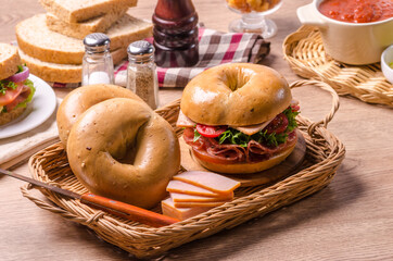 Hams with set of Fresh healthy bagel sandwich with ham, salami, tomatoes and vegetable in basket on wooden table
