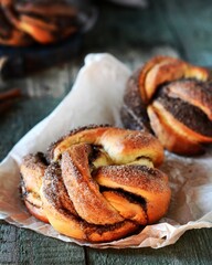 Braided buns with cinnamon on a wooden background, rustic style