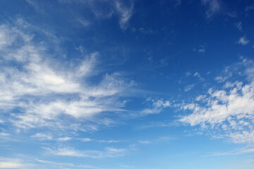 Naklejka na ściany i meble White cirrus clouds against the dark blue sky.