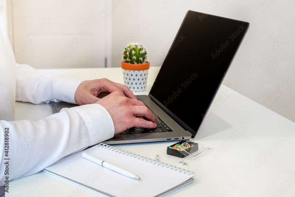 Sticker a male programmer works in front of a laptop screen in a bright office or remotely from home. workpl