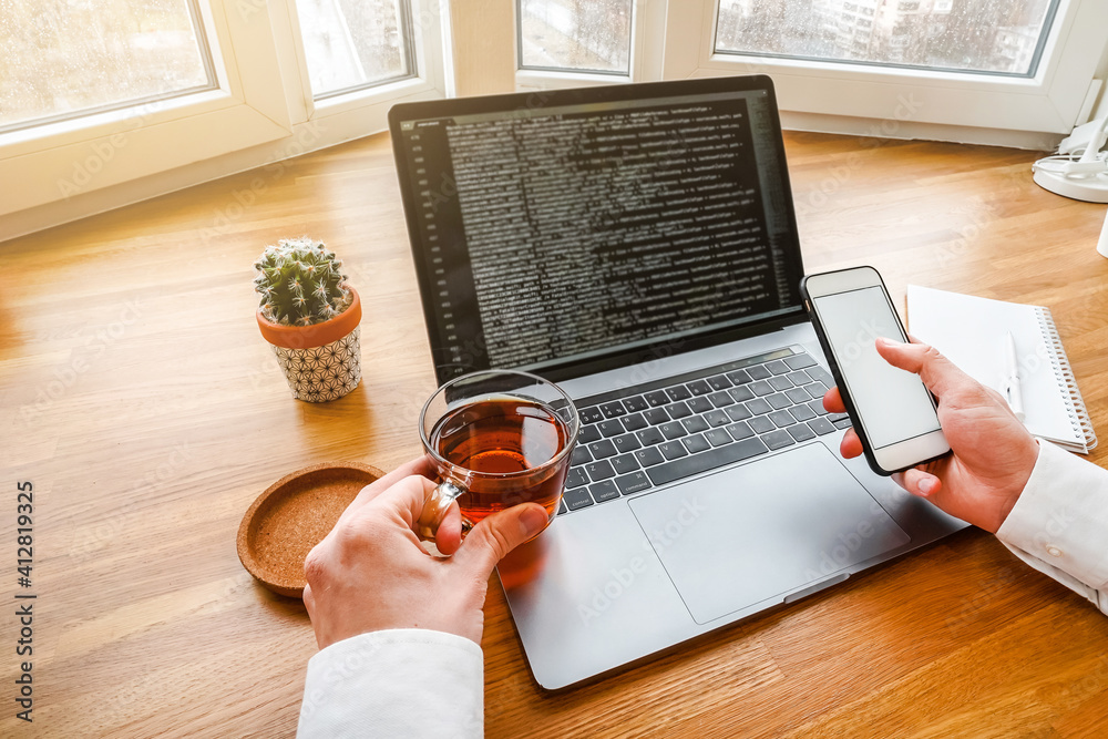 Canvas Prints the man works with modern technologies, a laptop and a mobile phone. top view of a programmer or bus