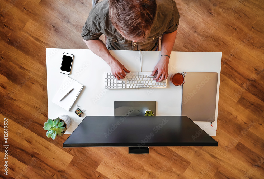Canvas Prints a male programmer works in front of a laptop screen in a bright office or remotely from home. workpl