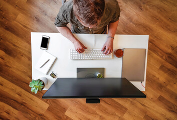 A male programmer works in front of a laptop screen in a bright office or remotely from home. Workplace