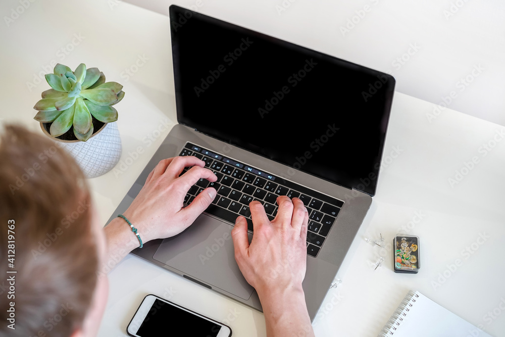 Poster a male programmer works in front of a laptop screen in a bright office or remotely from home. workpl