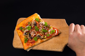 Slice of pizza on kitchen board. Just baked pizza. Pizza on black background.