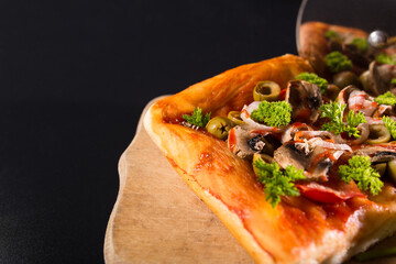 Cut5 pizza on black with copy space. Cutting pizza close up. Roller knife for pizza. Serlving pizza on black background.