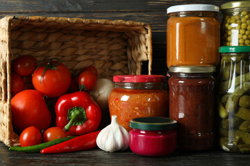 Jars with different canned food on wooden background