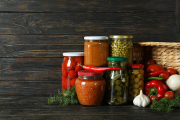 Jars with different canned food on wooden background