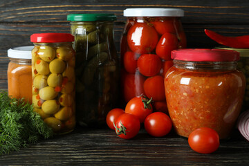 Jars with different canned food on wooden background