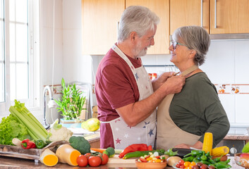 Two smiling seniors in the home kitchen prepare vegetables together for a healthy soup. Joyful elderly couple who appreciate a vegetarian lifestyle and enjoy their retirement