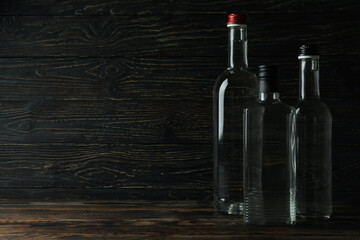 Blank bottles of vodka on wooden background, space for text