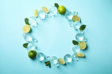 Shots of tequila or vodka, lime, mint and ice on blue background, top view
