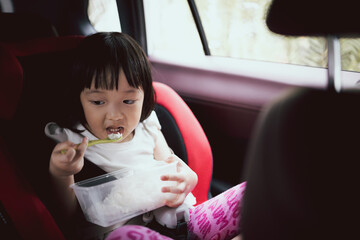 Asian cute girl having lunch in car seat. Concept for family life in car. On the go meal.