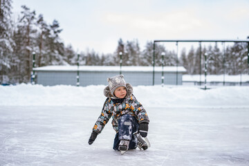Fototapeta na wymiar cute little boy learning to skate on a rink. Image with selective focus