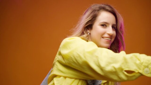 Trendy young woman dacing against yellow background