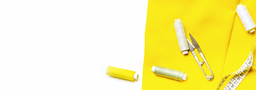 Tailoring concept. beautiful yellow fabric with sewing thread and tape measure, scissors, clarc . Top view. Flat lay