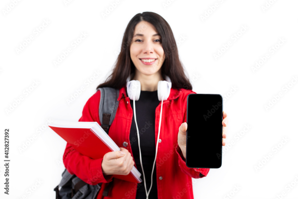 Wall mural young student woman showing a mobile phone to the camera.