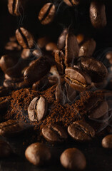Coffee beans falling on ground coffee on the table. The aroma of roasted arabica and robusna coffee beans. Dark background and beige toning