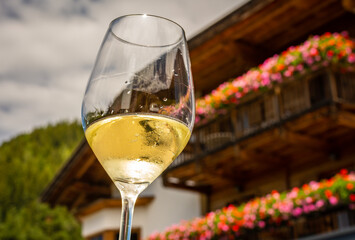Glass of  white wine on a typical South Tyrolean house background. Hiking in Dolomites, South Tyrol, northern Italy