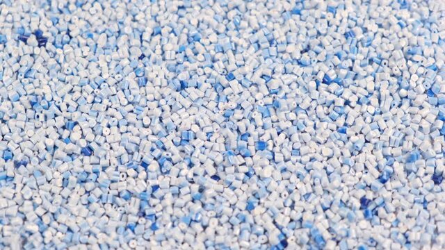 Secondary granule made of polypropylene, Light blue Plastic pellets crumbles to the table. Plastic raw materials in granules for industry. Polymer resin. Raw plastic recycling concept