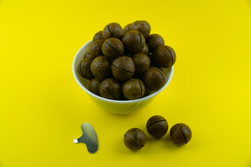 Macadimi nuts in a white cup on a yellow background.